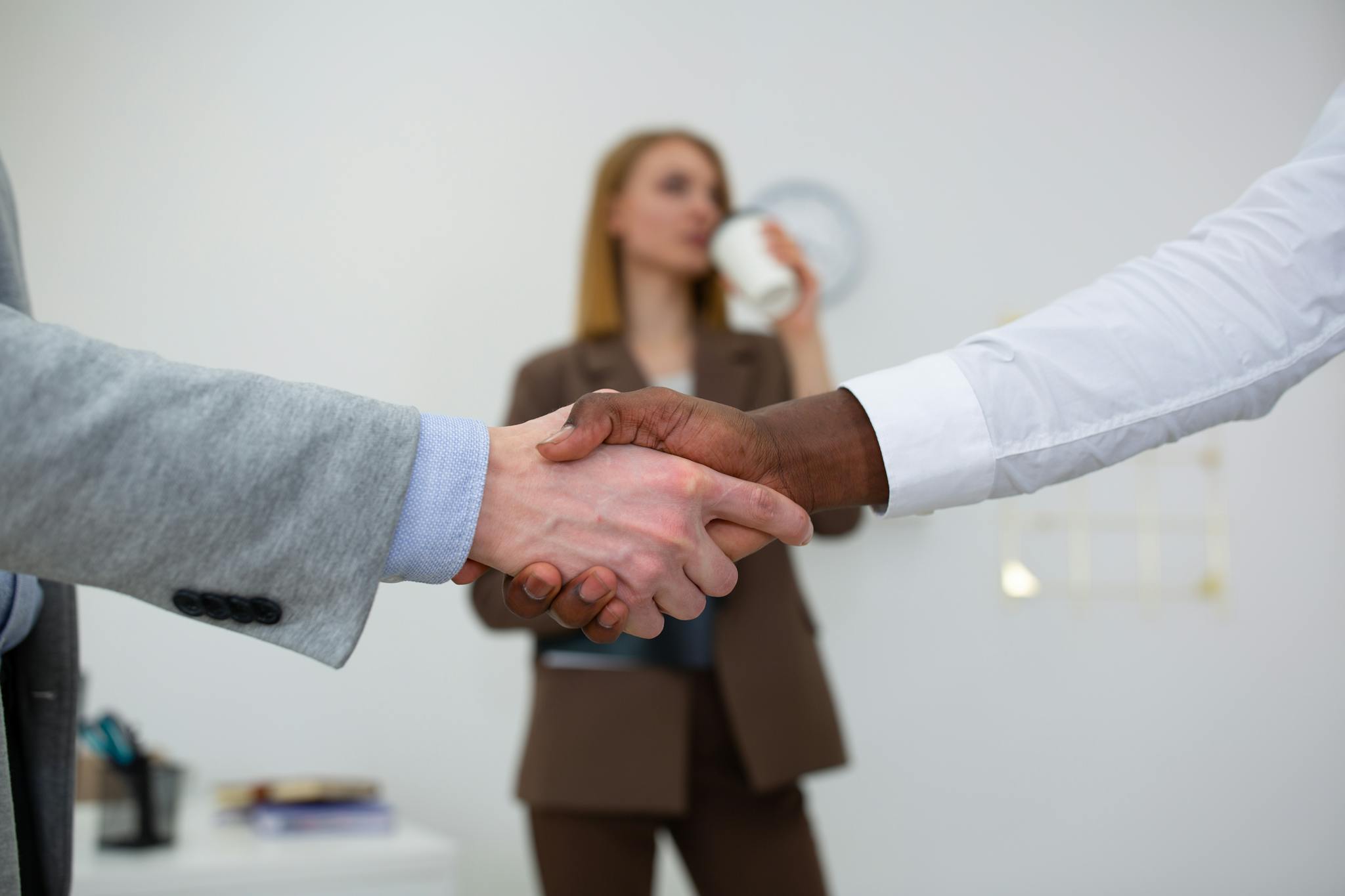 Close-up of diverse colleagues shaking hands in a modern office setting.