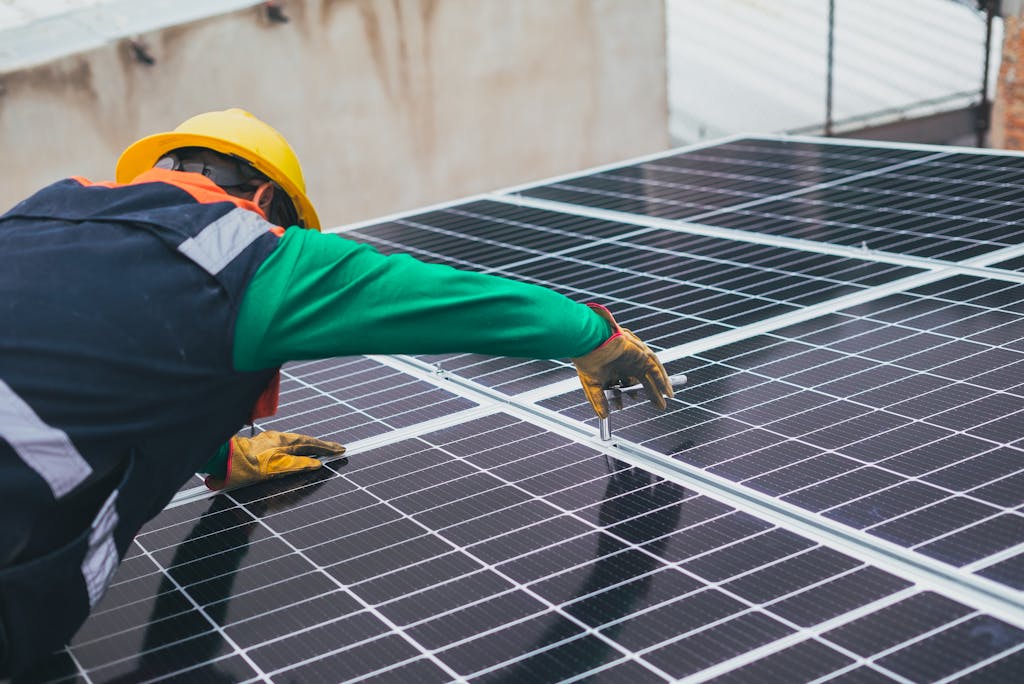 Technicien installant des panneaux solaires sur une toiture dans le cadre d’une solution énergétique durable.